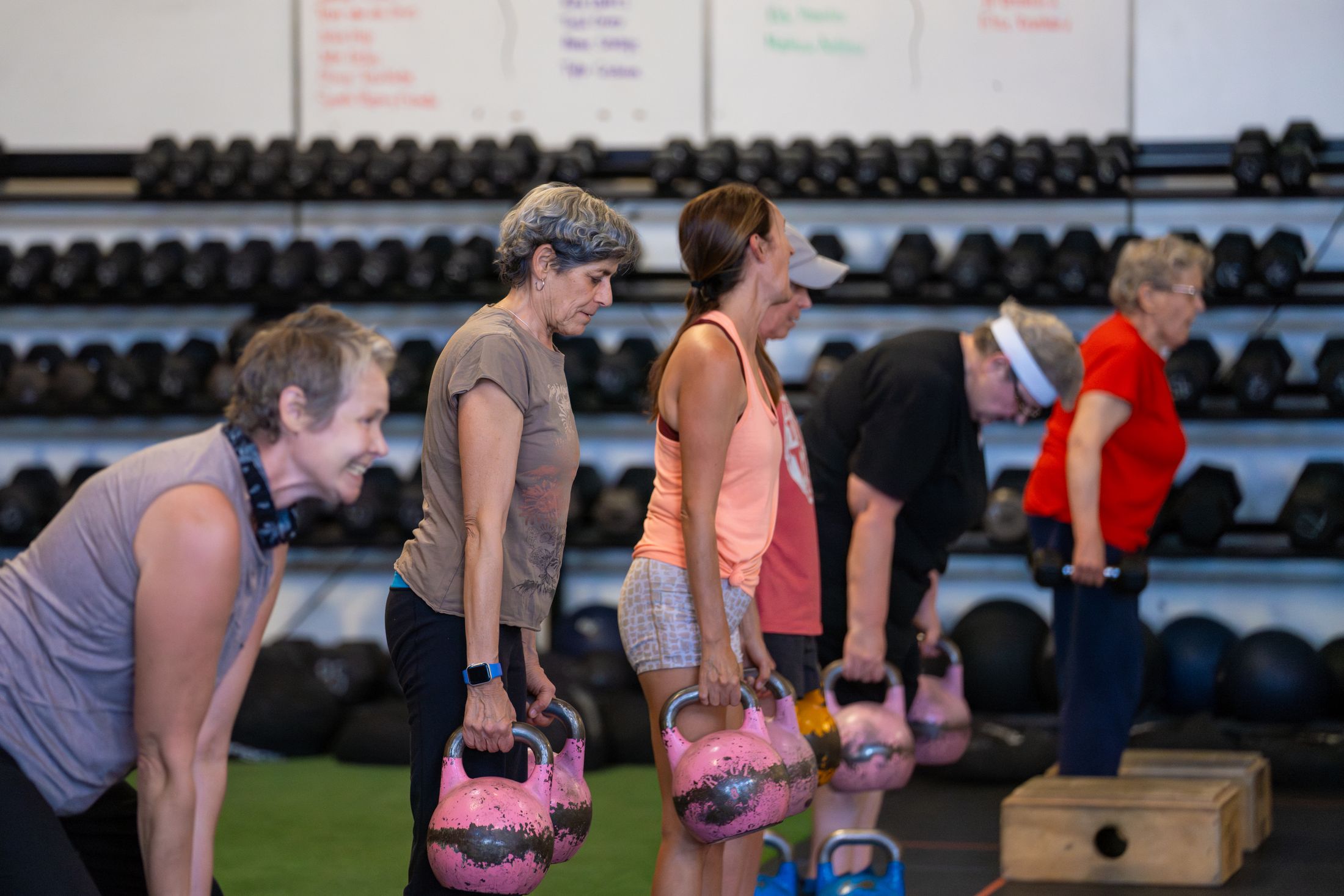 Participants smiling as they lift kettlebells together