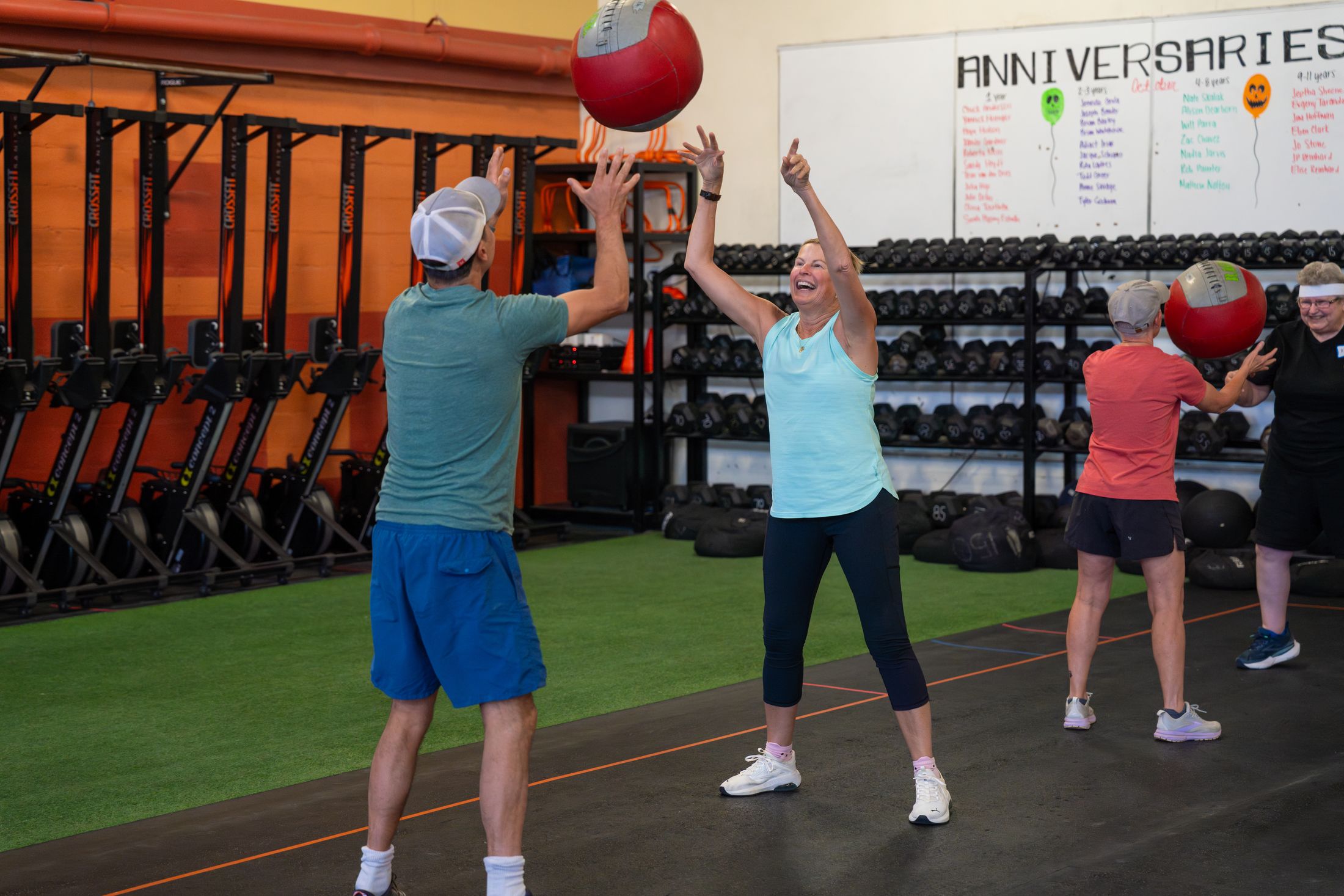 Two participants toss a medicine ball overhead on the turf