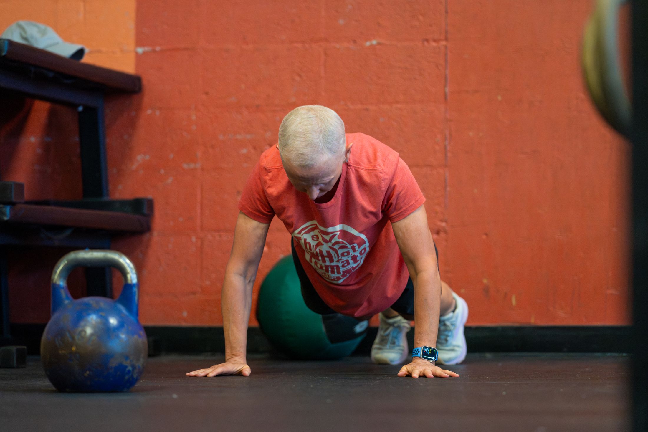 A participant holds a push-up position against the terracotta wall